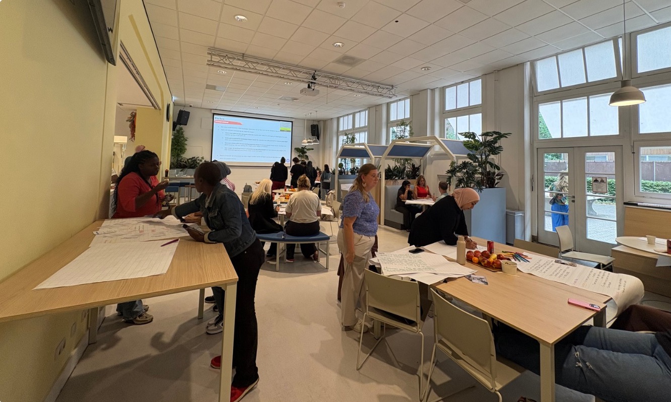 Deelnemers werken in kleine groepen aan onderwijsontwerpen in de bootcampruimte