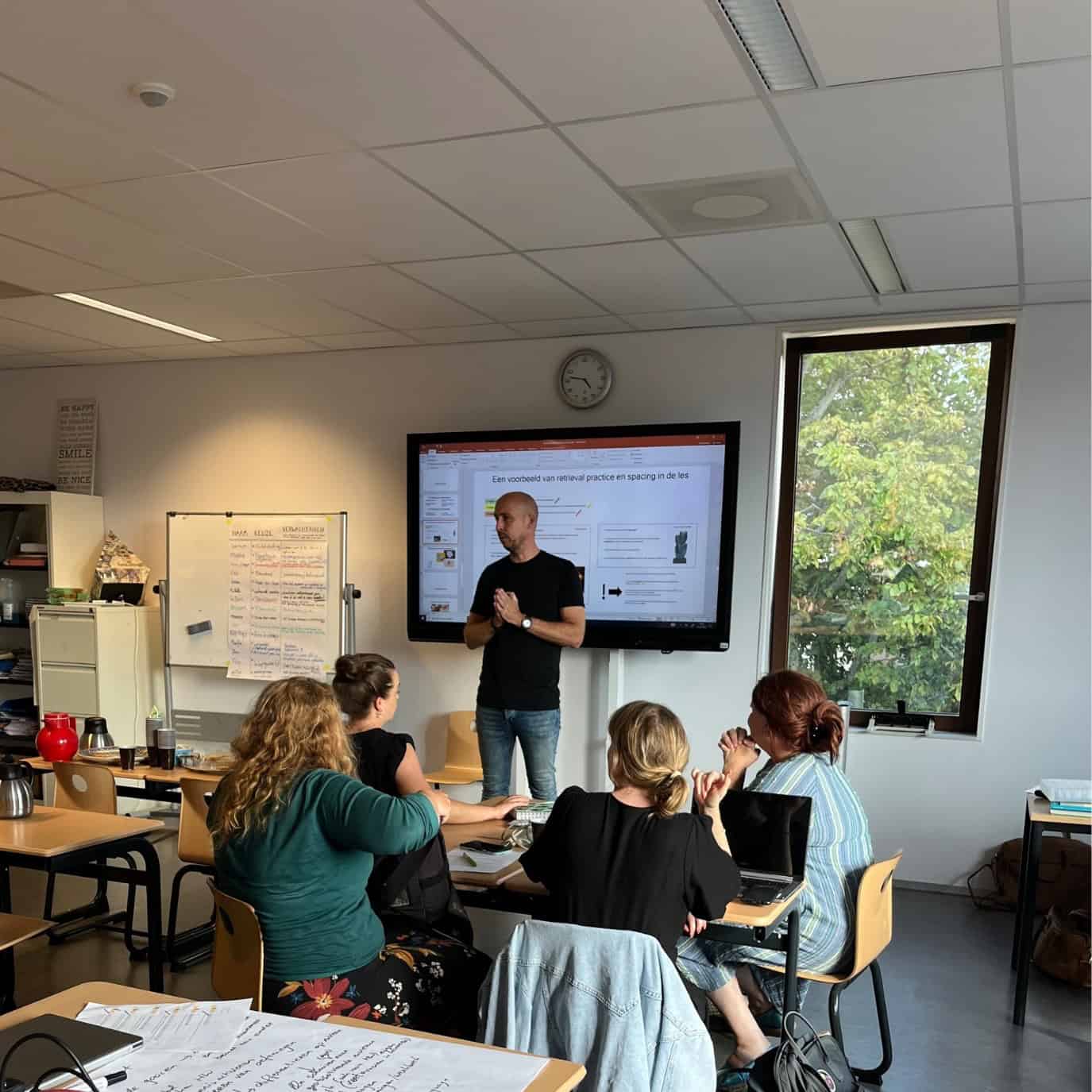 Een trainer geeft uitleg aan een groep docenten in een klaslokaal